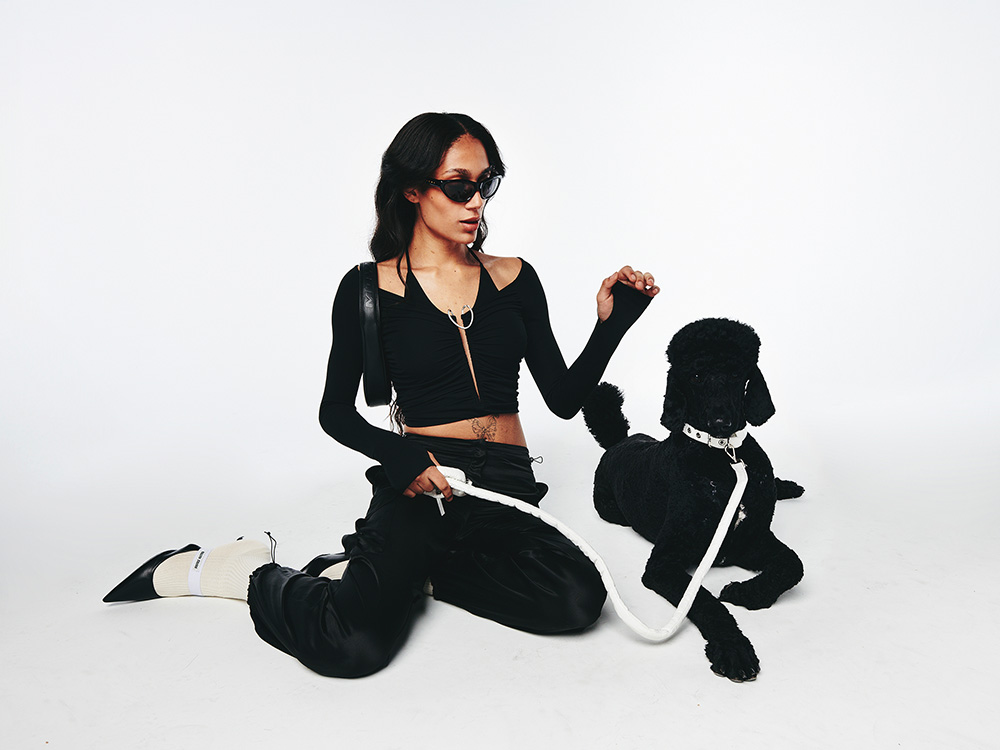 a person in all black on the ground with a black dog in a white collar