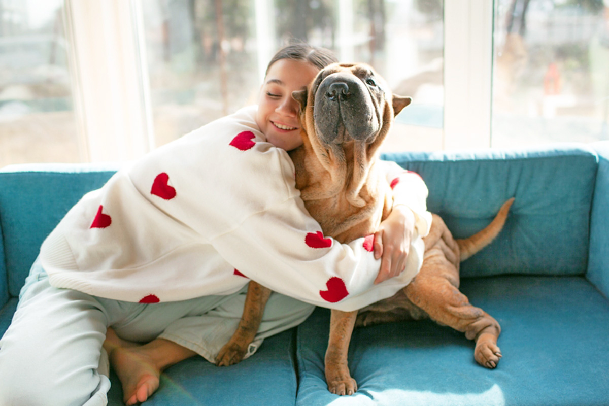 woman hugs dog on the couch 