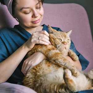 Woman looking closely at her cat's skin.