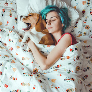 Woman sleeping in bed with her beagle dog.