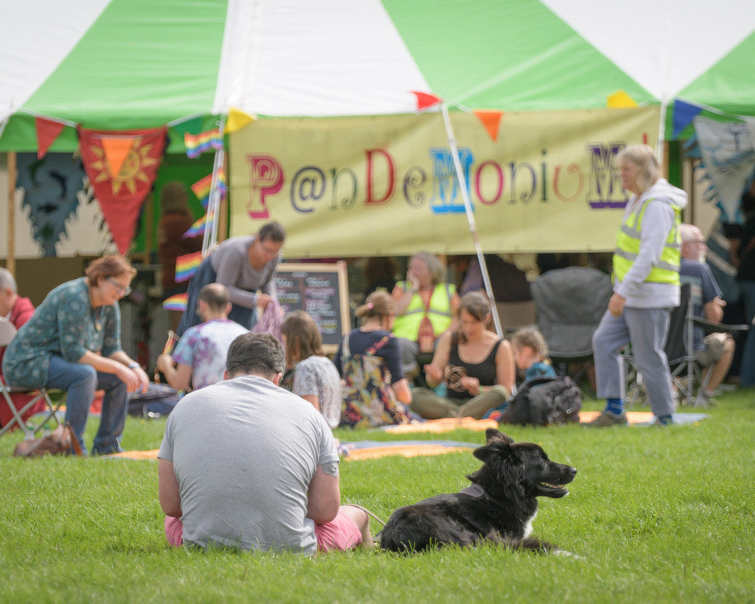 dog and human sitting on the grass at a festival