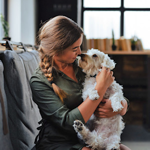 Woman snuggling her dog at home.