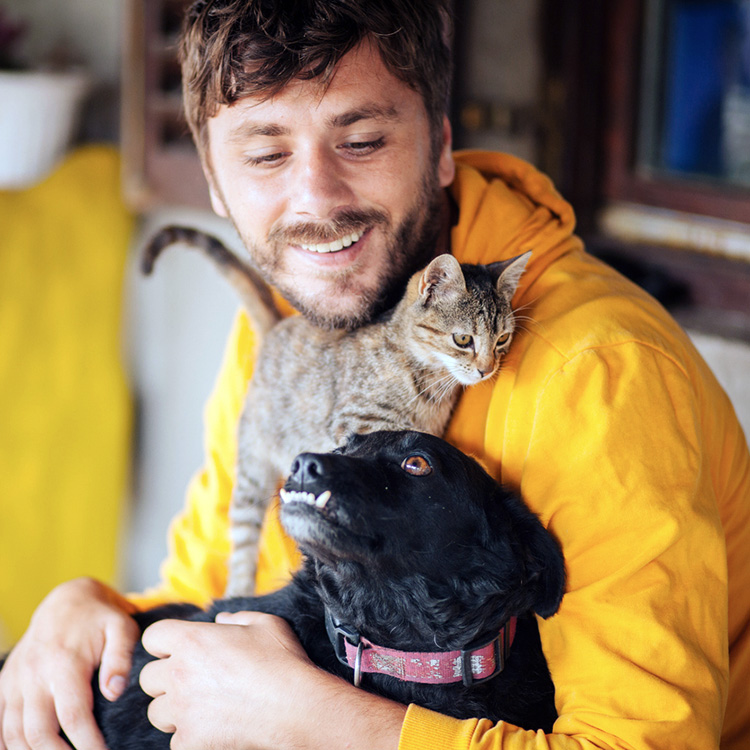 Man holding his pet dog and cat.