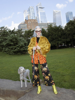 A fashionable woman standing outside with her dog in the city. 