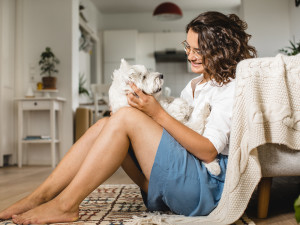 Woman sitting on the floor holding a white mixed breed dog in a relaxed living room setting