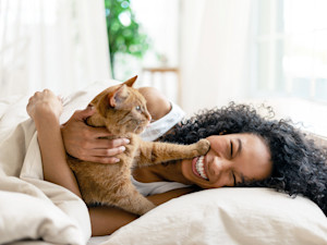 Woman laughing with her cat at home.