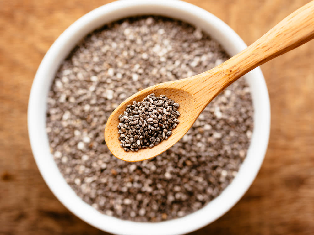 a bowl of brown chia seeds with a spoon scooping