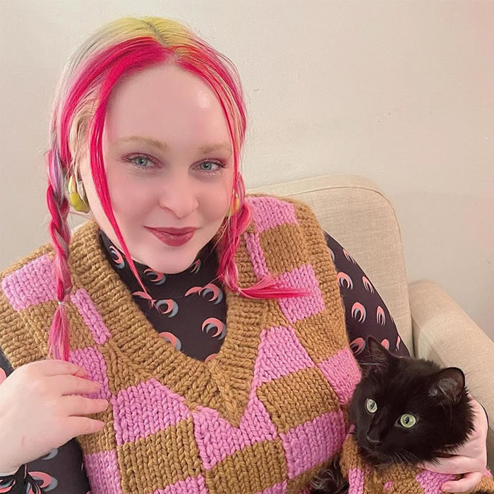 a human and their cat in matching sweaters