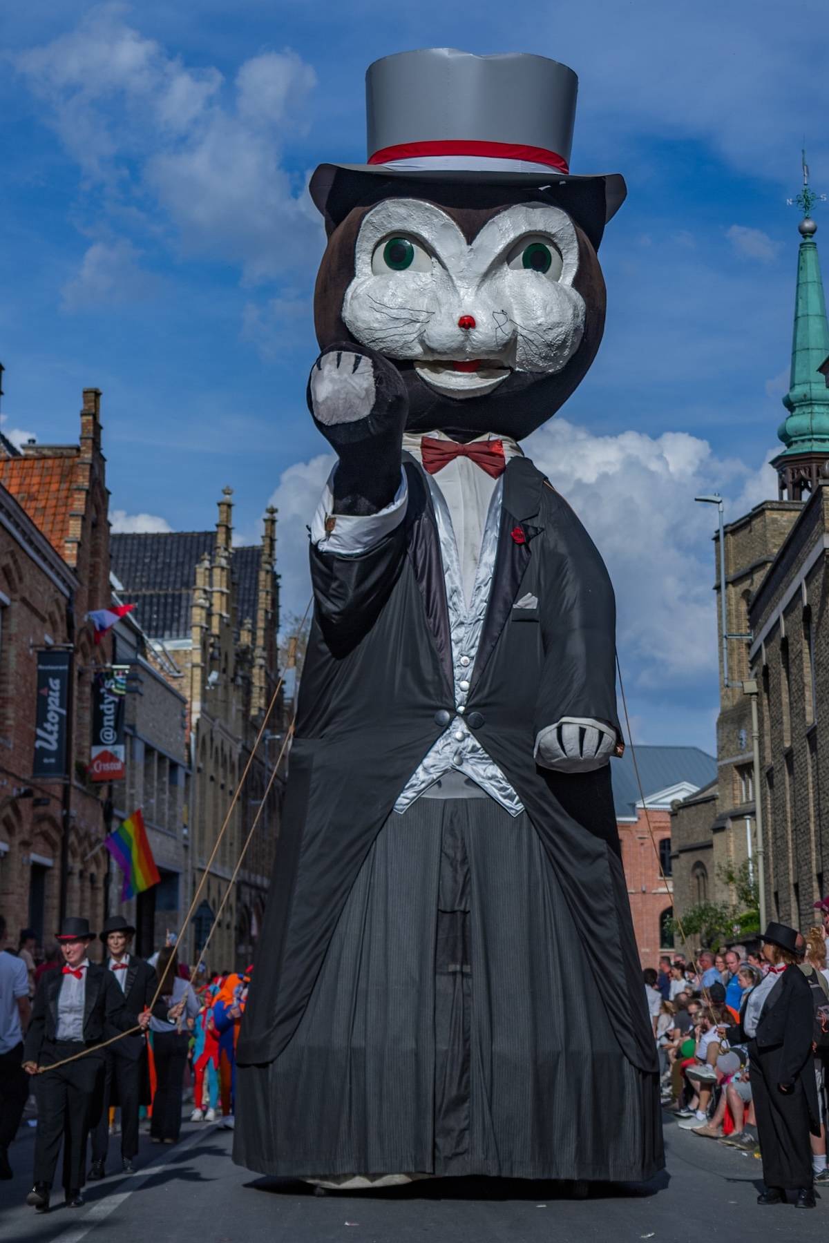 a picture of a giant black cat in a suit in a parade