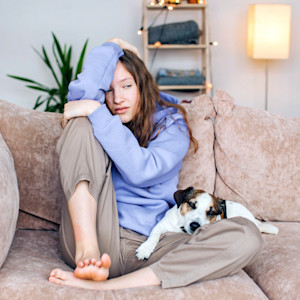 Woman sad and stressed with her small dog at home.