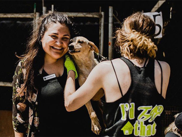 A woman smiling with a dog at an animal rescue service event. 