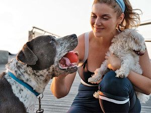 Woman playing with her dog and his ball outside.