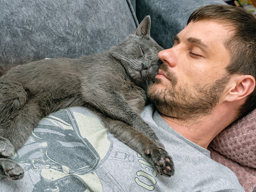 Cat sleeping on man's chest at home.