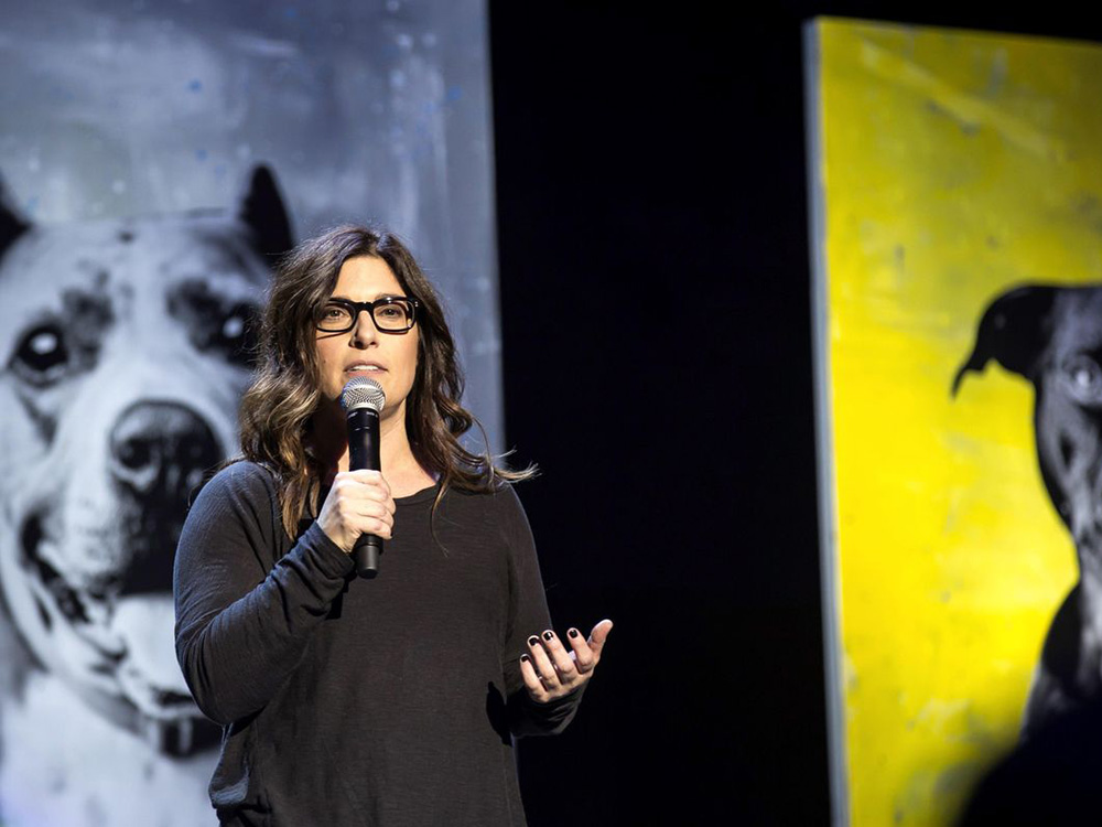 Corry speaking at event with dog behind