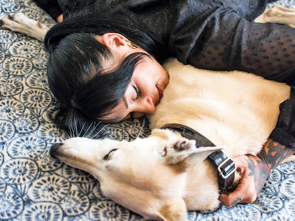 Woman cuddling her dog on the floor at home.