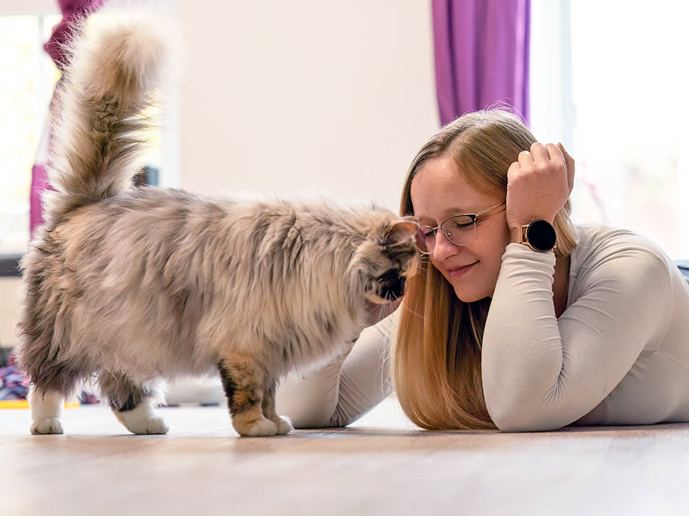Woman snuggling her cat at home.