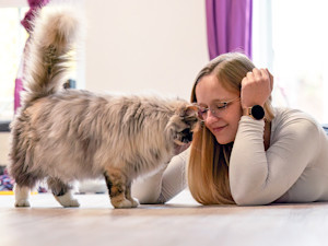 Woman snuggling her cat at home.