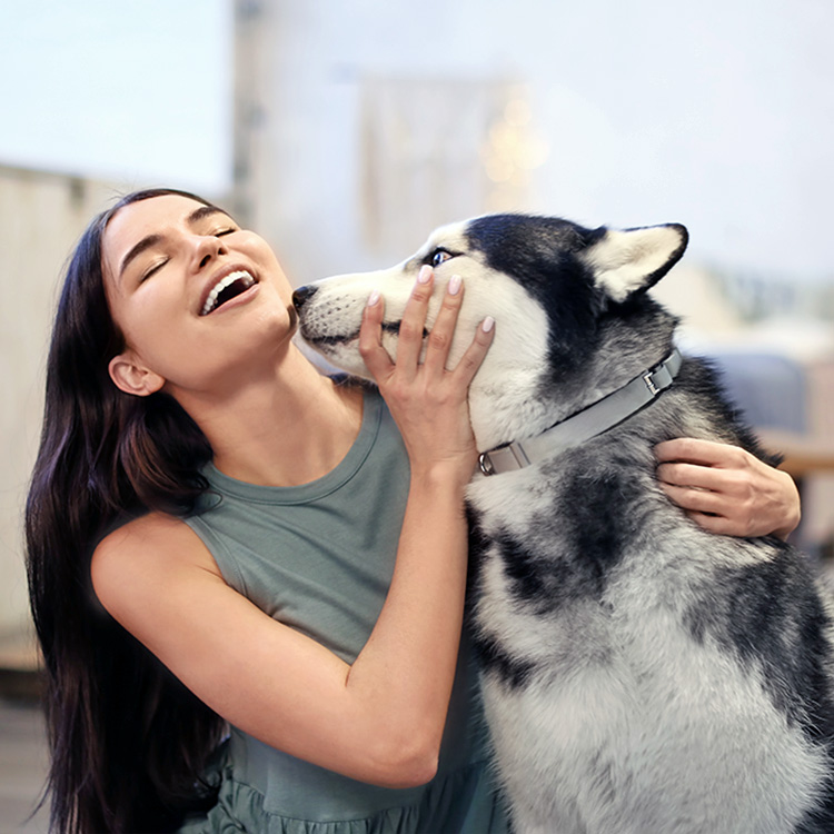 Woman turning away from her husky dog's mouth.