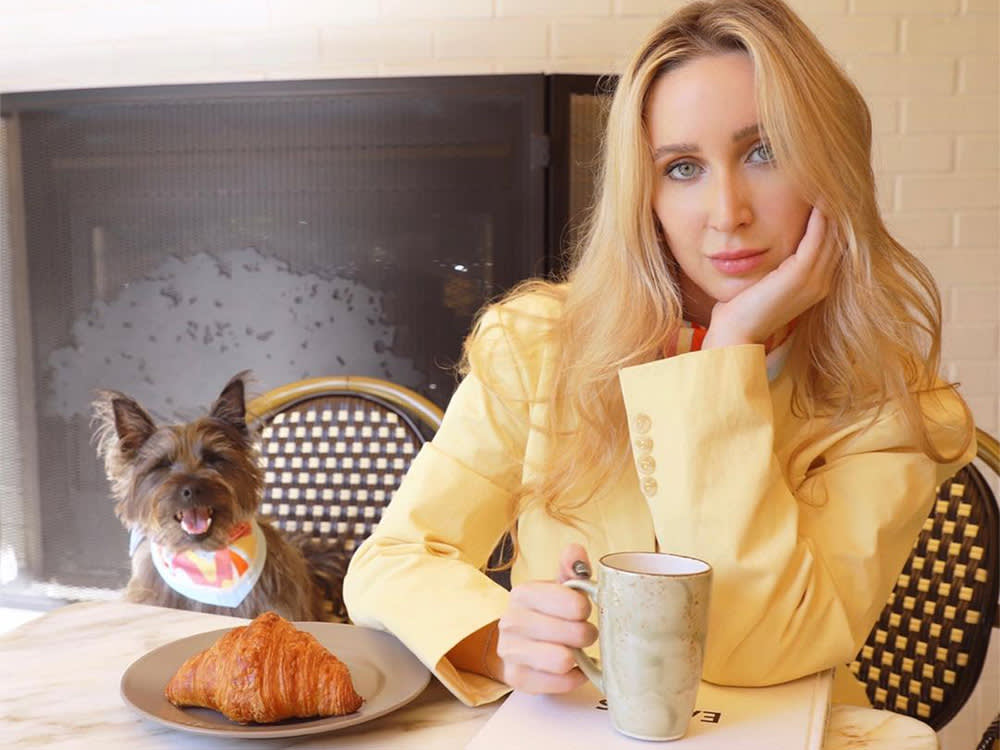 shelby with dog daisy at dining table with a croissant