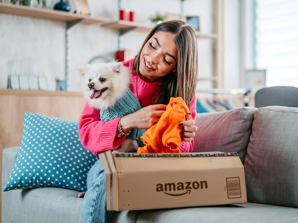 Woman opening package with her small white dog.