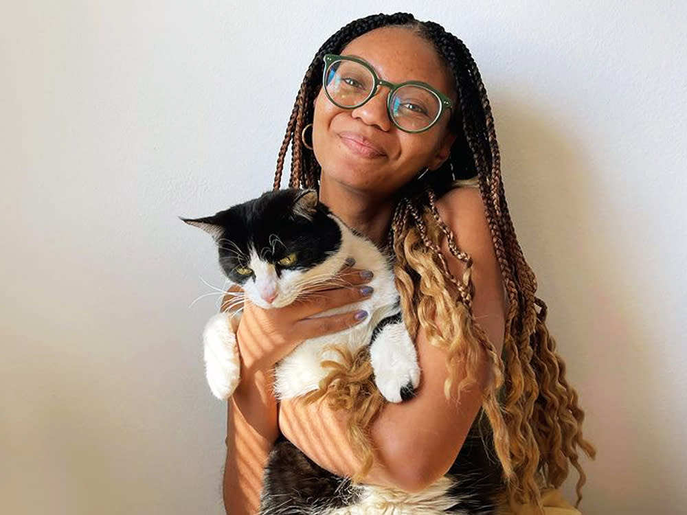 Leah Thomas smiles with her black and white cat