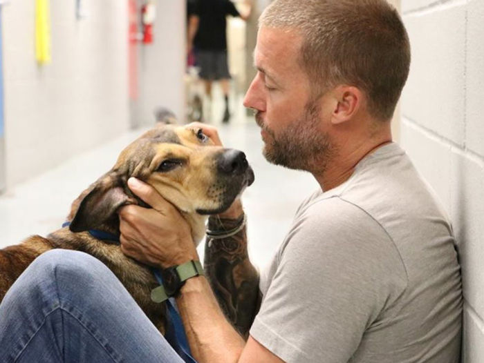 Zach Skow pets a dog inside a prison