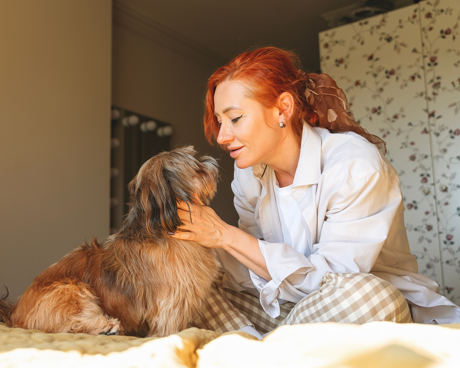 red head woman and dog cuddling on a bed