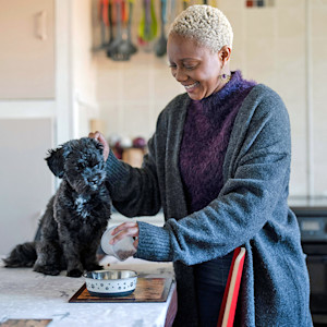 Woman feeding her dog at home.