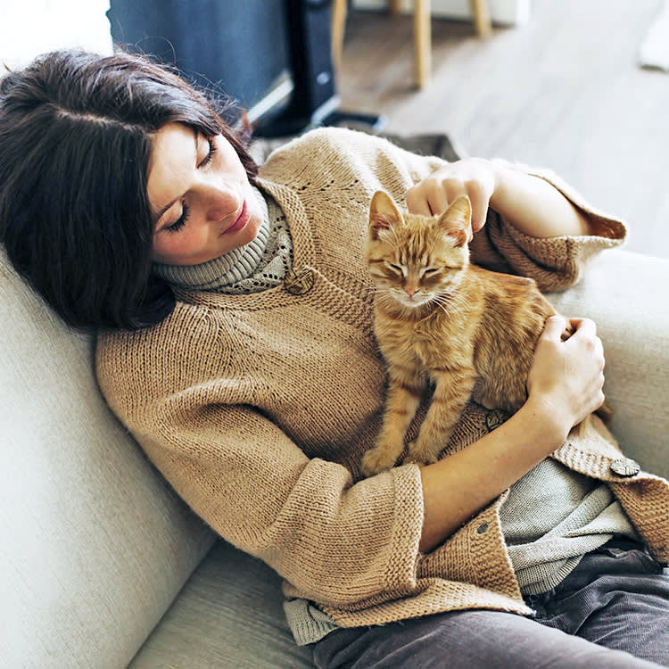 Woman snuggling her kitten on her lap.