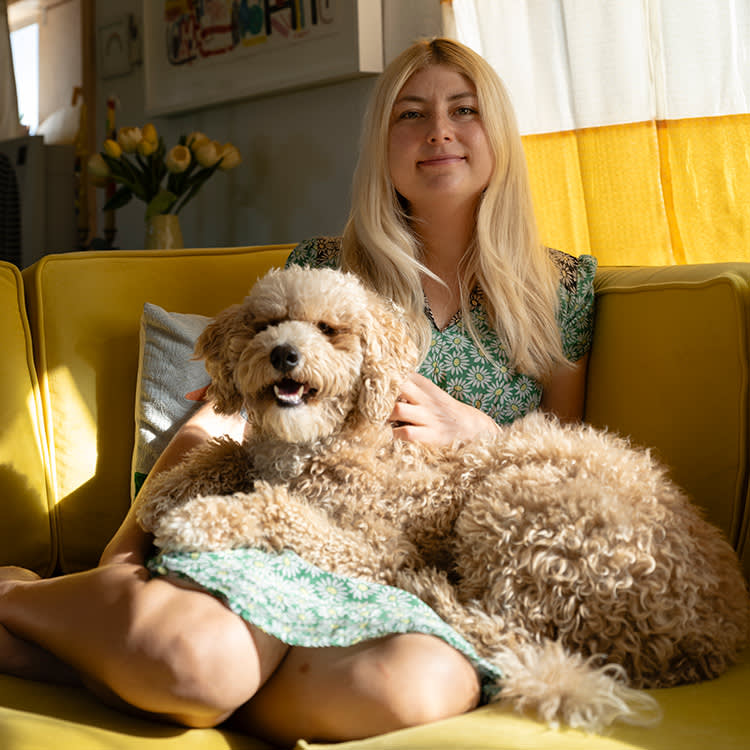 Lorien Stern with her dog on a yellow couch