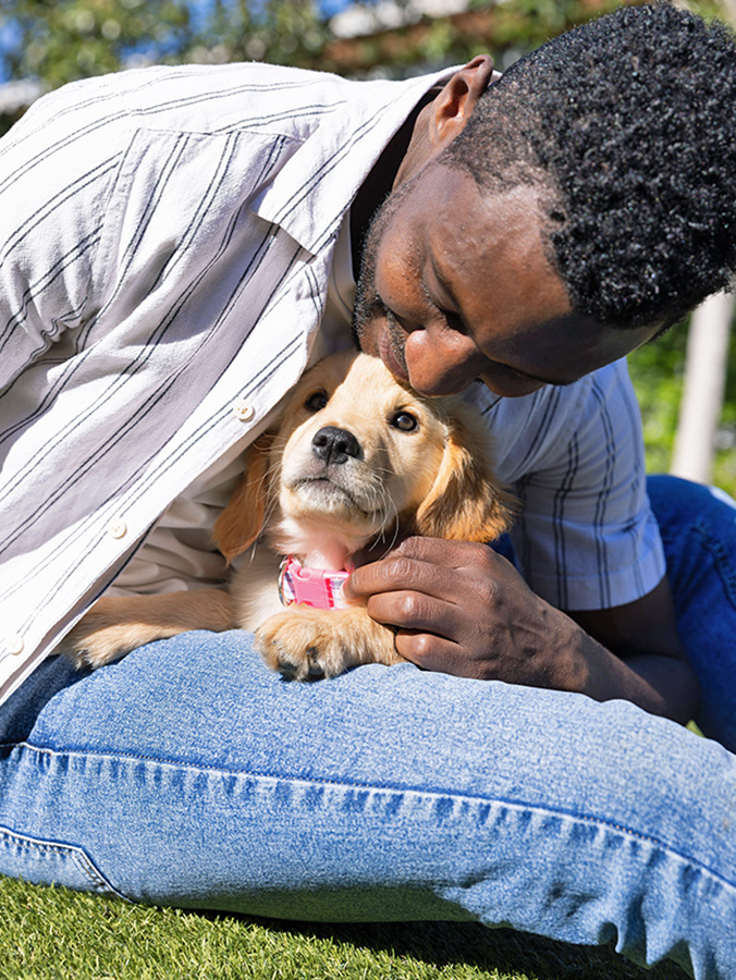 Man holding puppy outside in grass.