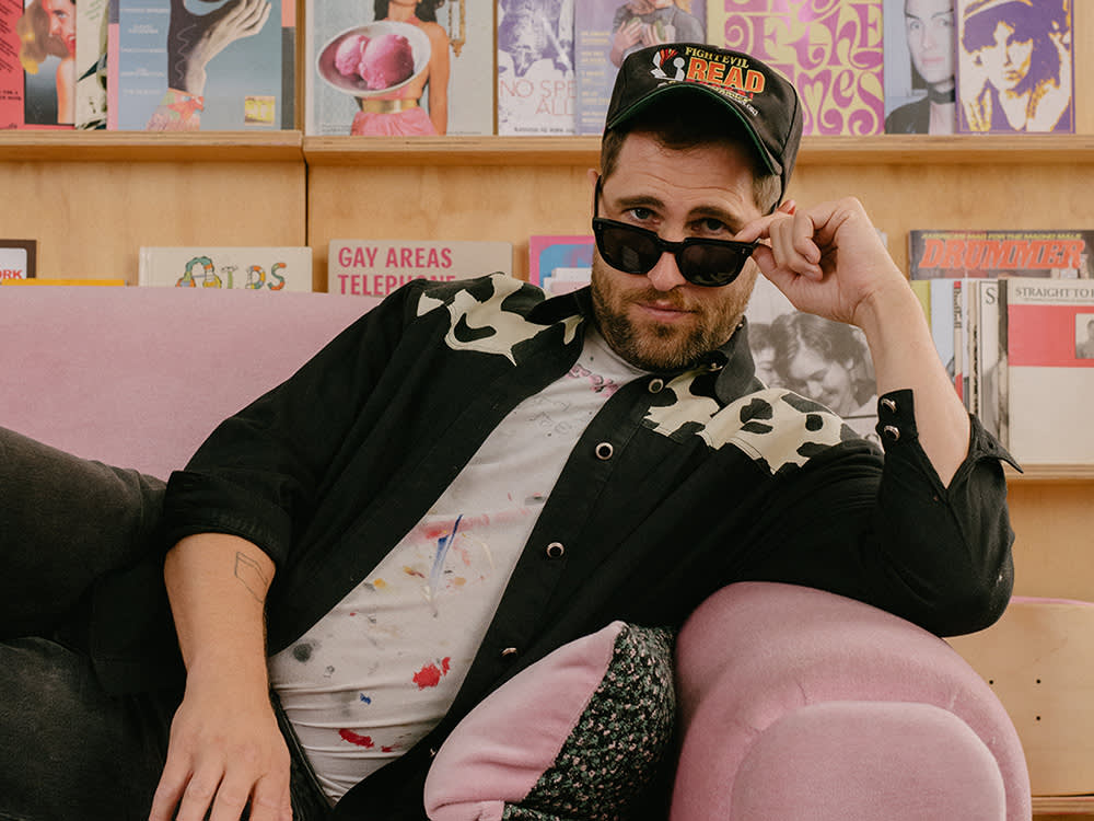 Seth Bogart sits on a pink couch