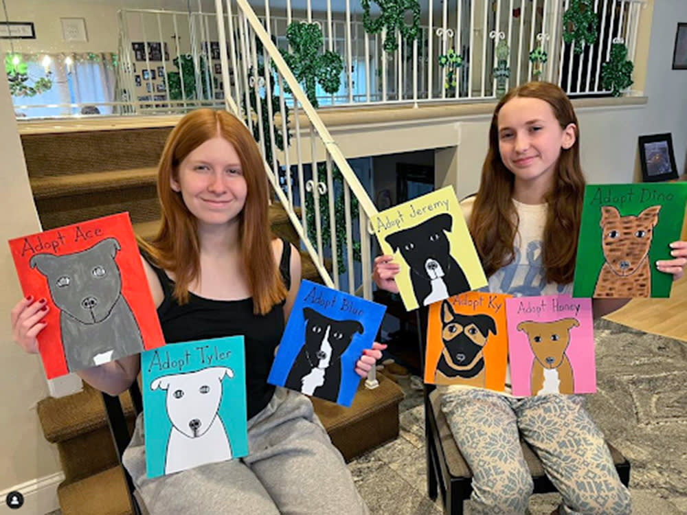 Two girls showing off shelter dog paintings.