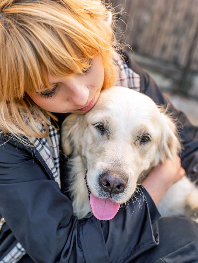 Woman hugging her senior Golden Retriever dog.