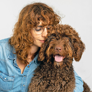 Curly haired woman and her brown poodle mix dog.