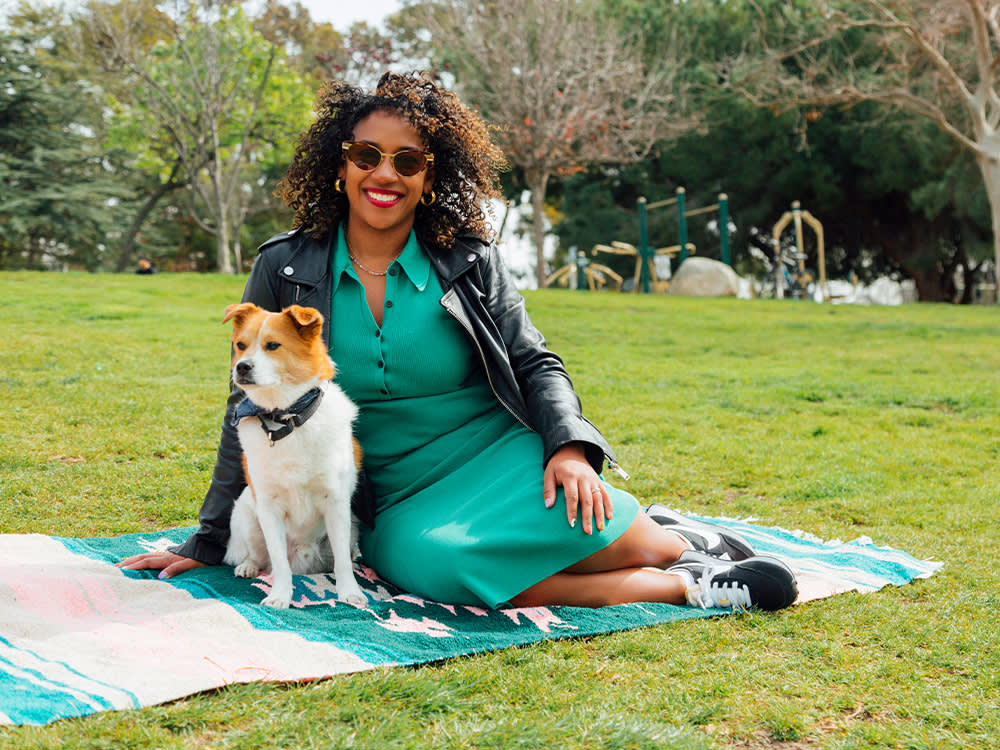Dayna Isom Johnson with her small white and orange dog on a picnic blanket