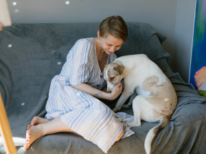 Woman hugging her dog while sitting on the couch.