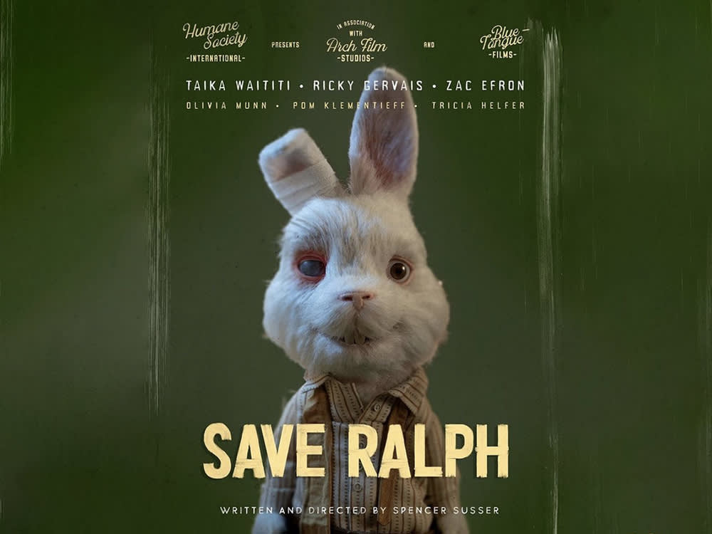 Poster for the short film "Save Ralph" showing a puppet-like white rabbit with a red eye and a bandaged ear in front of an olive background with the actors names and sponsors names across the top