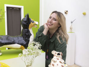 Katie Kimmel smiling with a selection of ceramic pet artwork pieces. 