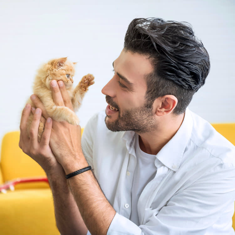 Man holding up a small kitten.