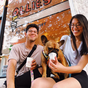 A happy couple feeding their dog ice cream outside of Ollie's ice cream shop. 