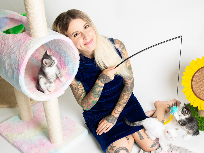 Hannah Shaw holds a cat toy for three small kittens