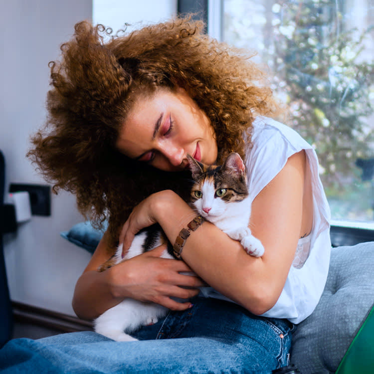 a woman with curly red hair hugs her cat tight