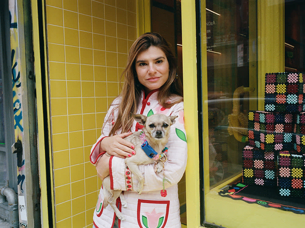 A woman holding a dog in front of a store. 