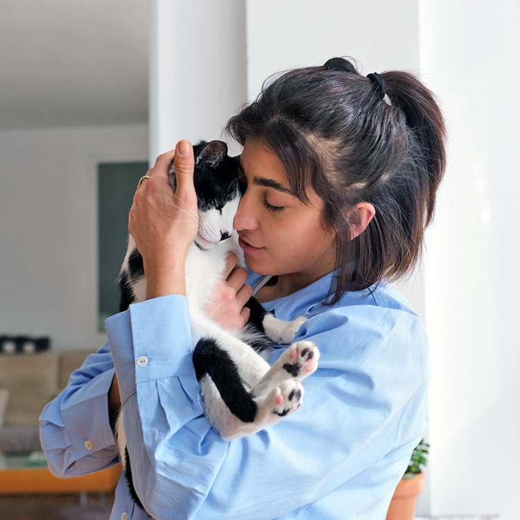 Woman hugging cat to her face at home.