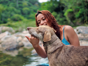 Woman talking to her dog outside in the river.