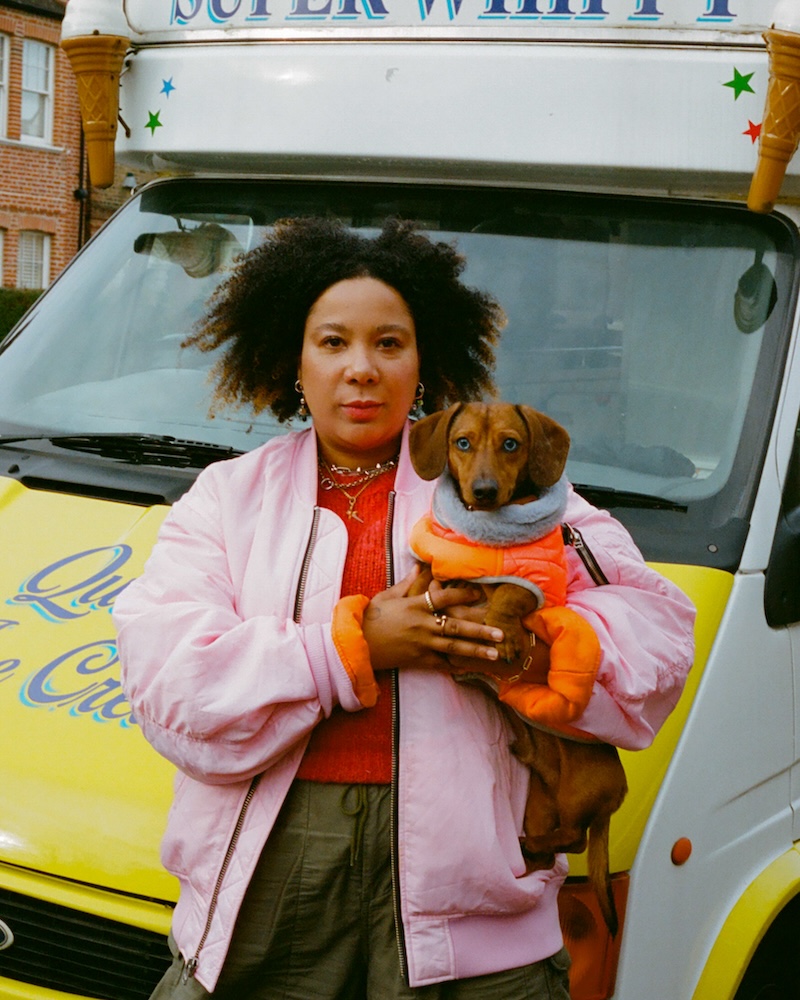a woman with black curly hair holds a daschund
