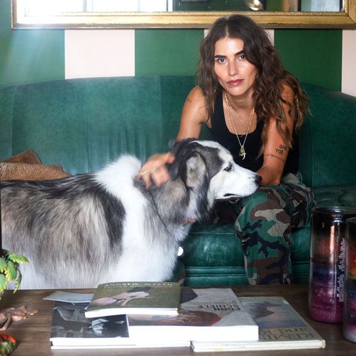 Langley Fox petting her Husky mix dog while sitting on a green couch in her living room