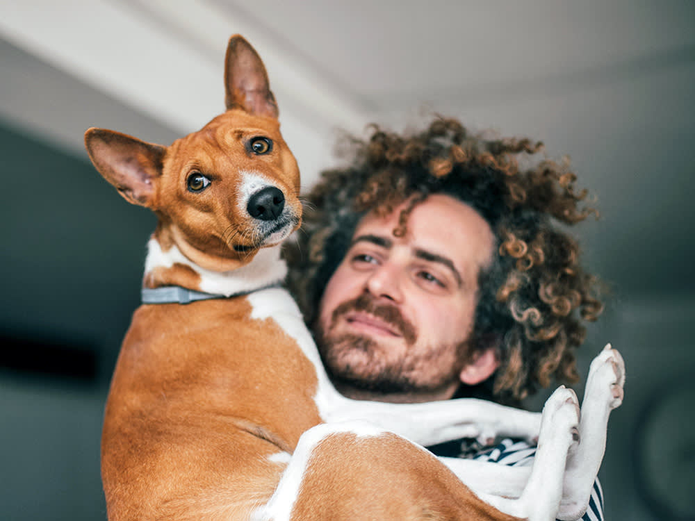 Man holding his dog in his arms at home.