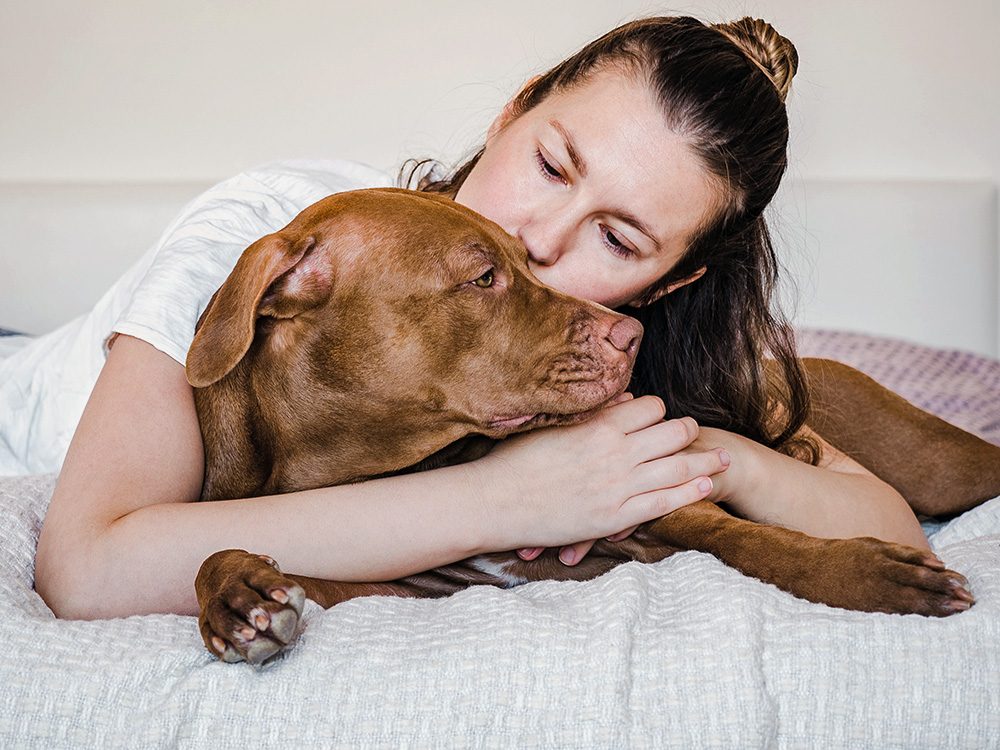 Woman cuddling her brown dog at home.